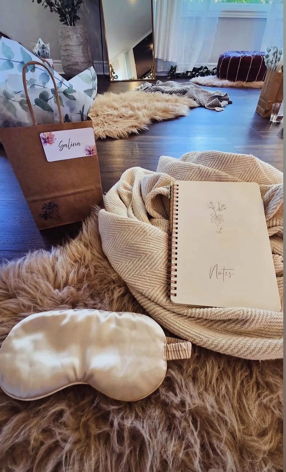A welcome gift flatlay with a notebook, eye mask, and gift bag