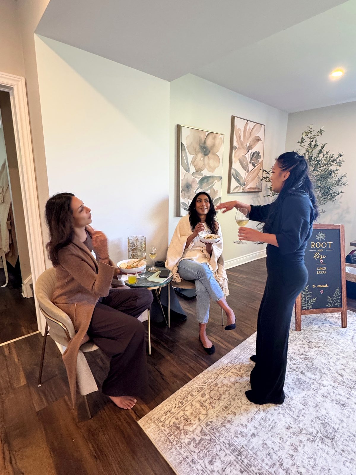 Trisha pouring a glass of wine and sharing a toast at a Root and Rise gathering
