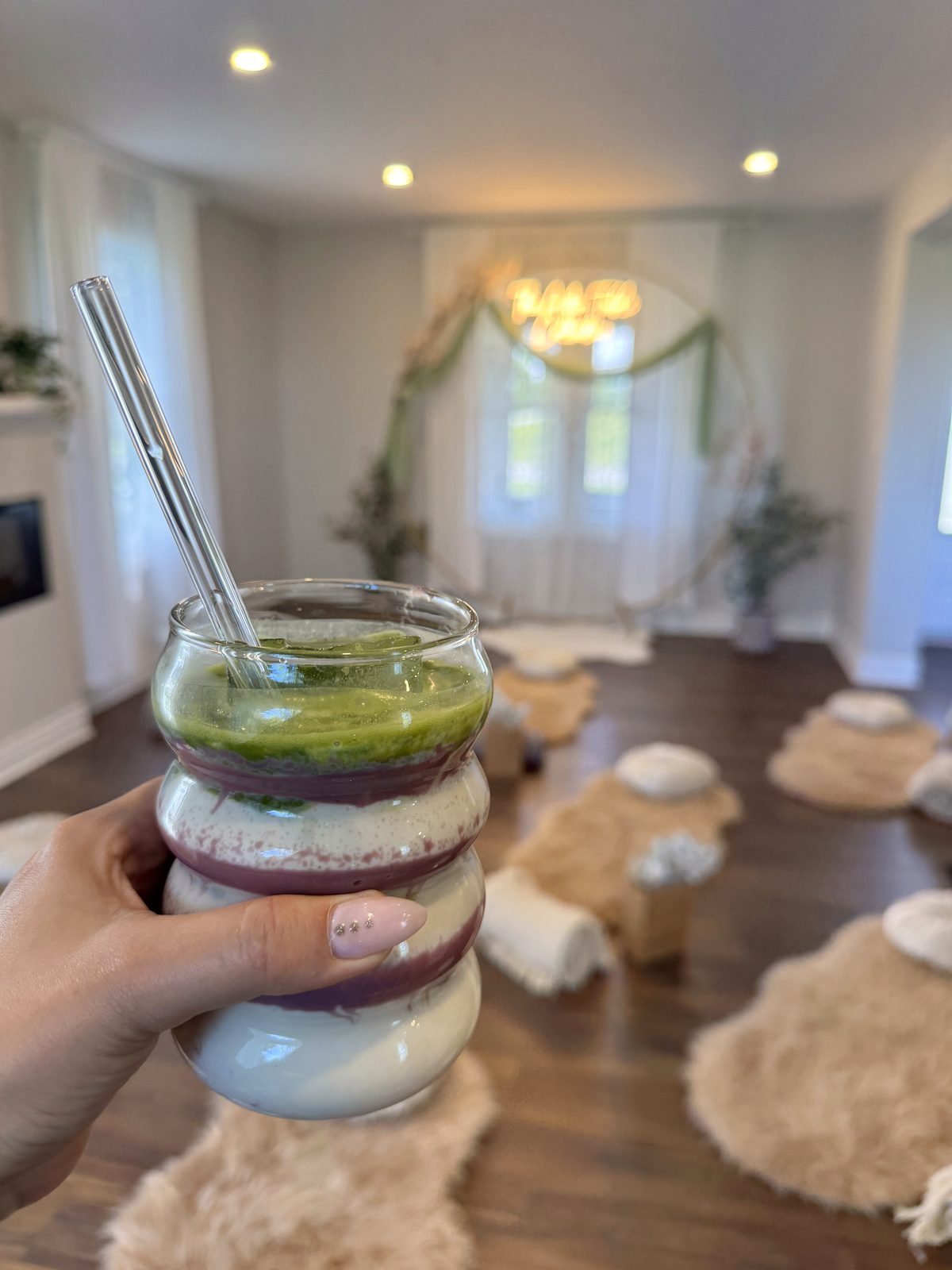 A layered matcha smoothie held up in the breathwork room